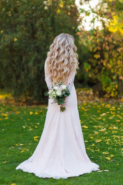 Photo mariée en robe se tient avec son dos dans le jardin