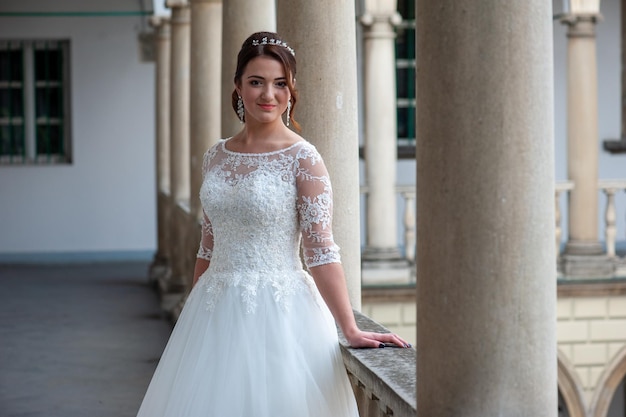 Une mariée se tient sur un balcon dans une robe de mariée