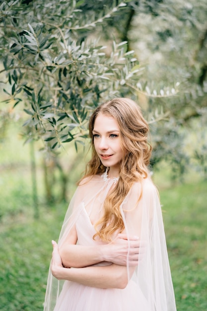 La mariée se tient les bras croisés sur sa poitrine dans une belle robe