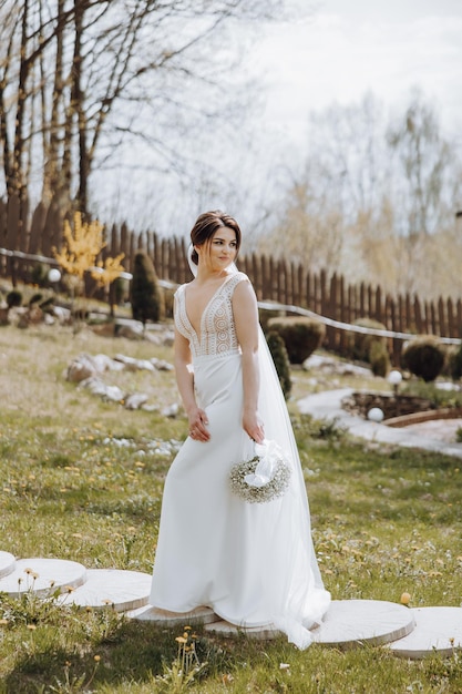 Une mariée se tient dans un champ avec un bouquet de fleurs.