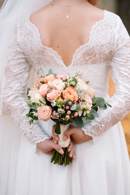 La mariée se tient dans une robe de mariée blanche avec un bouquet