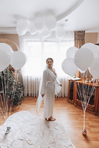 Une mariée se tient devant une pièce pleine de ballons blancs.