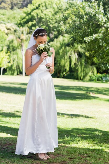 Mariée, sentir les fleurs dans le parc