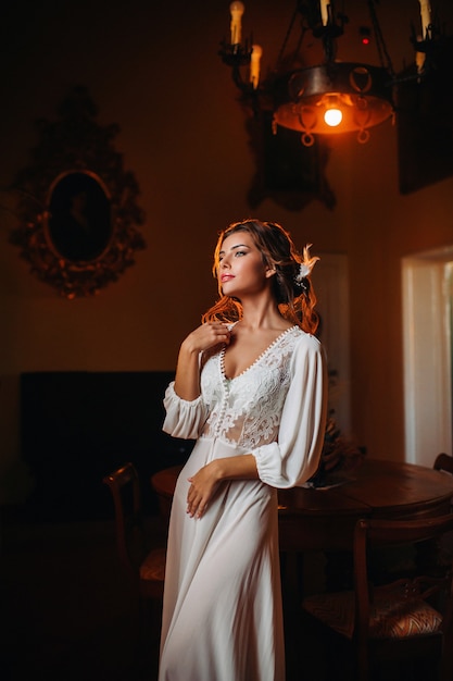 Une mariée en sous-vêtements et une robe blanche à l'intérieur d'une villa