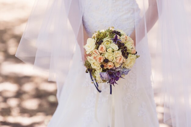 Mariée tenant un beau bouquet de mariée sur la promenade.