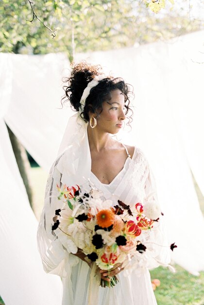 Photo la mariée tenant un bouquet debout à l'extérieur