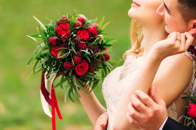 Mariée tenant le bouquet de mariage de belles pivoines rouges étreignant