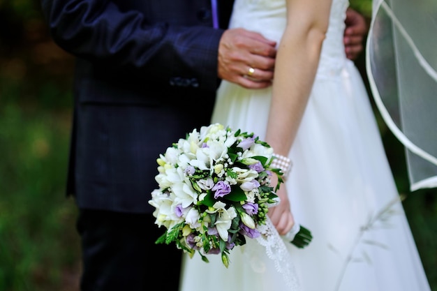 Mariée tenant le bouquet de mariage et le marié