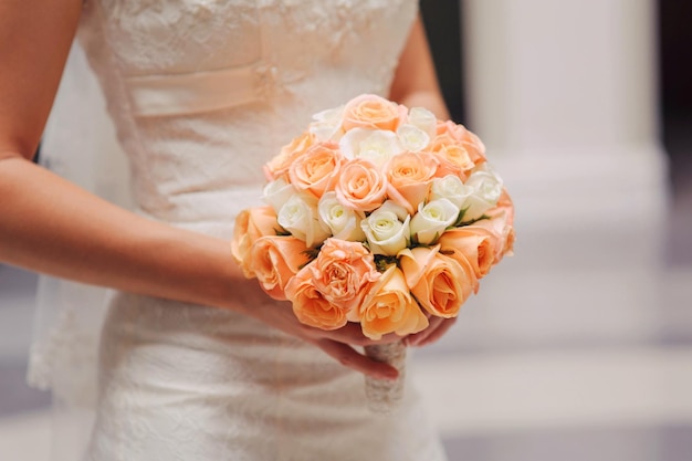 Mariée tenant un bouquet de mariée avec des roses blanches et roses