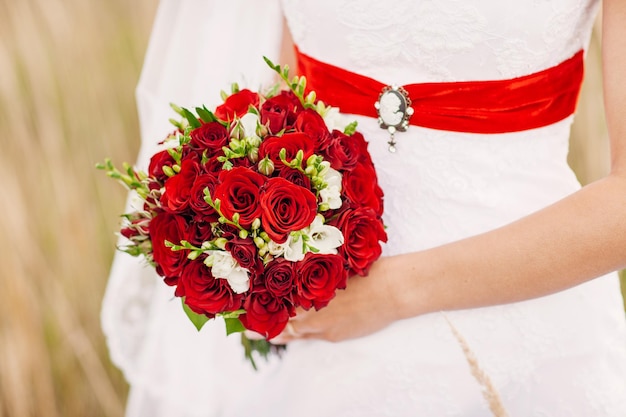 Mariée tenant son bouquet de fleurs de mariage rouge