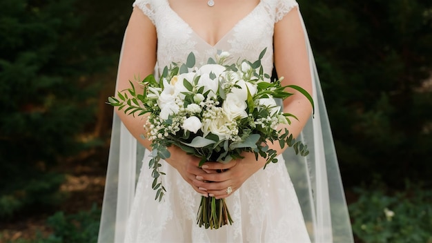 La mariée tient un bouquet blanc dans ses bras.