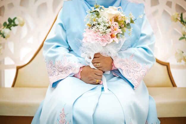 La mariée tient un bouquet de fleurs de mariage dans ses mains.