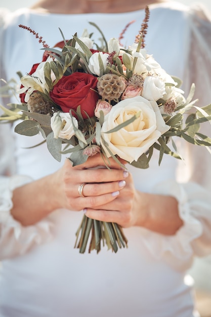 La mariée tient un bouquet de mariage dans ses mains