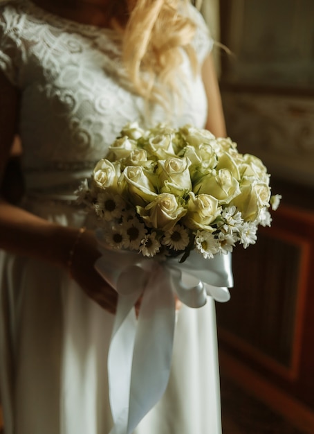 La mariée tient un bouquet de mariage de gros plan de roses.