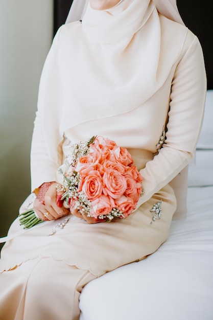 La mariée tient un bouquet de mariée dans ses mains.