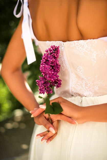 La mariée tient une brindille de lilas dans les mains. Mariage. Détails. Bokeh