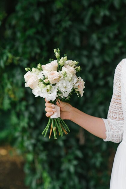 Photo la mariée tient dans ses mains un beau bouquet de fleurs blanches.