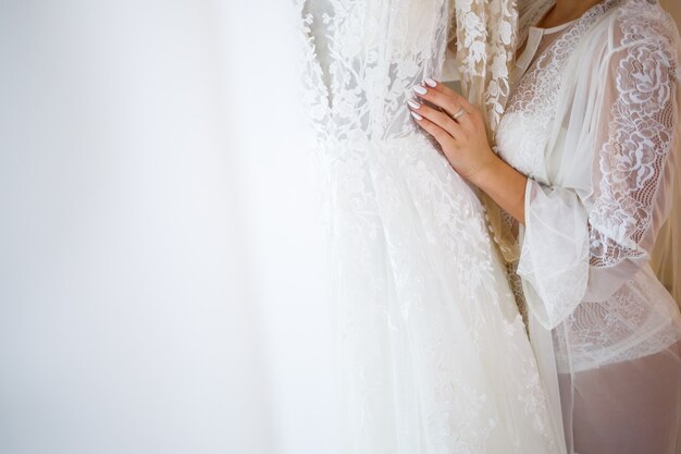 La mariée tient dans ses mains une belle robe de mariée