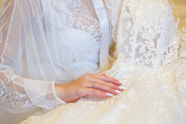 La mariée tient dans ses mains une belle robe de mariée