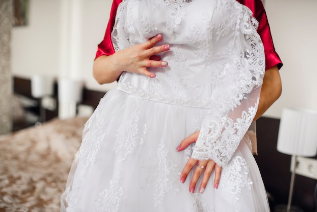 La mariée tient une robe blanche de mariage