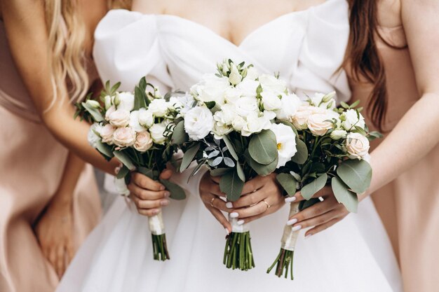 La mariée tient son bouquet de mariage avec les demoiselles d'honneur