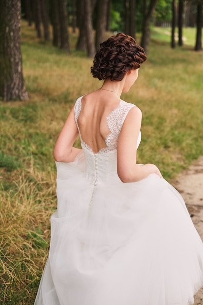 La mariée traverse la forêt avec une magnifique robe, concept de mariage