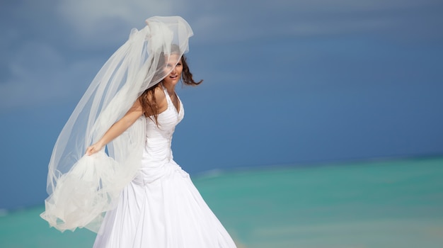 Mariée avec un voile sur la plage