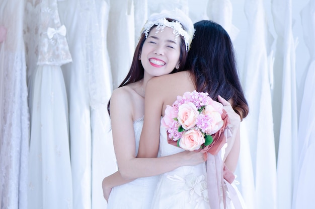Les mariées asiatiques embrassent joyeusement les mariées le jour du mariage tout en tenant des fleurs