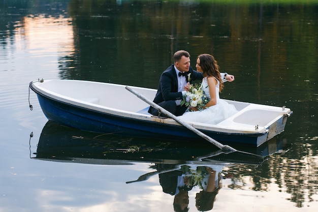 Les mariés dans une barque sur le lac au coucher du soleil