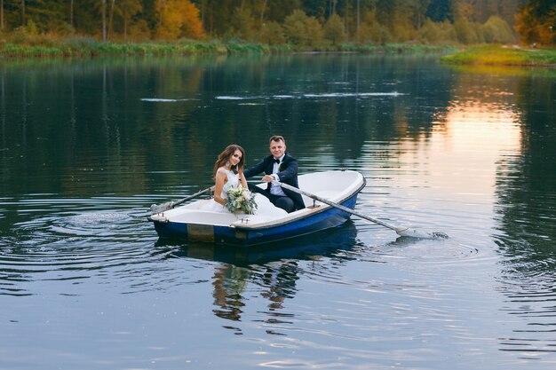 Les mariés dans une barque sur le lac au coucher du soleil