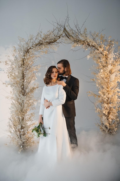 les mariés le jour de leur mariage près de l'arc festif