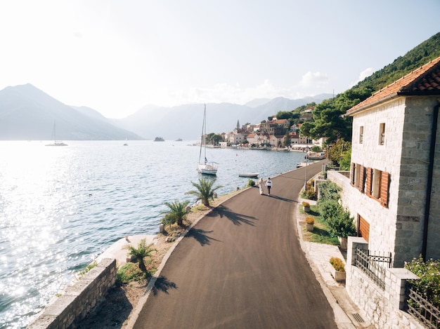 Les mariés marchent le long de la route goudronnée le long de la côte de perast monténégro