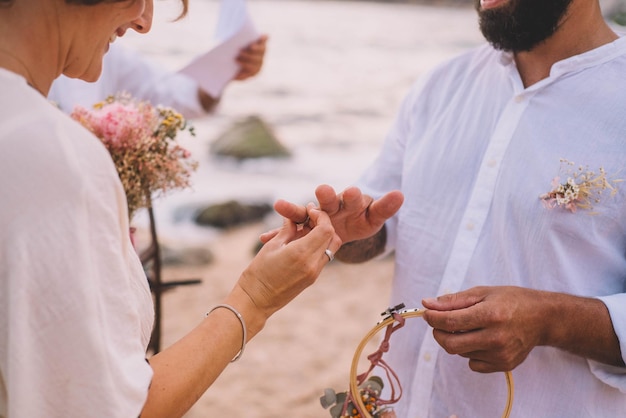 Les mariés mettent leurs bagues lors d'un mariage sur la plage