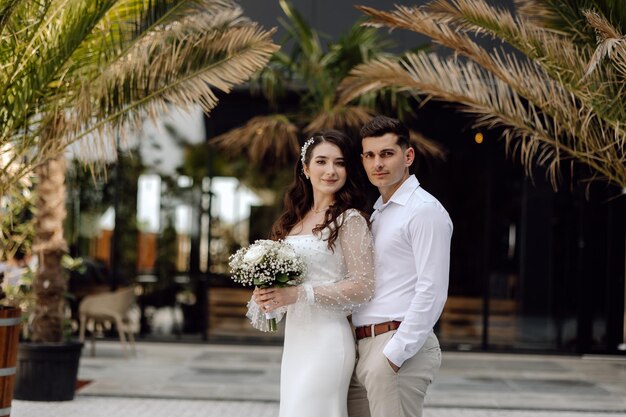 Les mariés posent pour une photo devant les palmiers du lieu du mariage