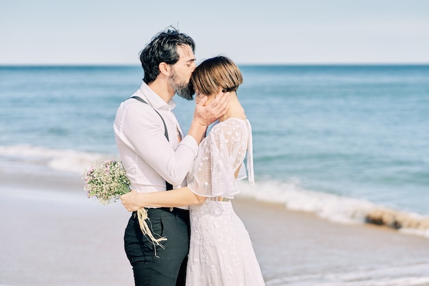 Les mariés s'embrassant sur la plage célébrant joyeusement leur mariage