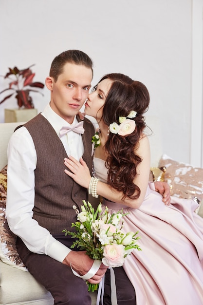 Les mariés s'embrassent et posent pour le mariage. L'amour et la tendresse dans chaque regard. Un couple amoureux s'embrasse à la maison. Un homme donne à une femme un bouquet de fleurs.