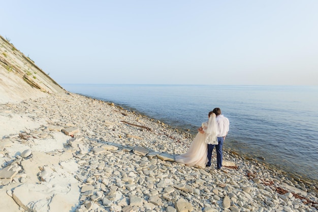 Les mariés s'embrassent et regardent la mer