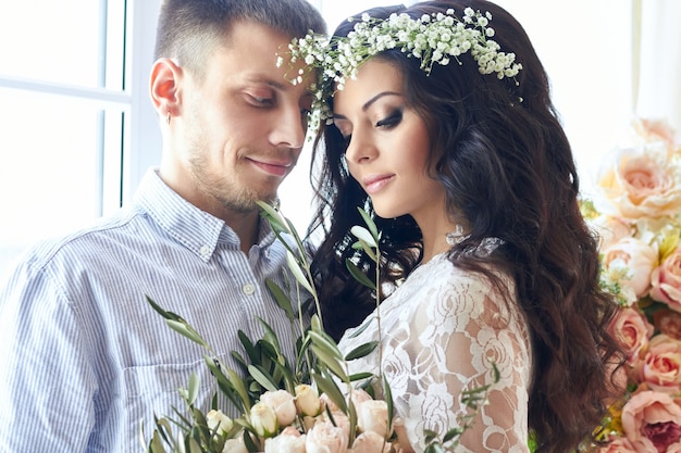 Les mariés se préparent le matin pour le mariage. Couple d'amoureux s'embrassant à la maison. Beau marié et charmante mariée. Les couples préparent la cérémonie de mariage