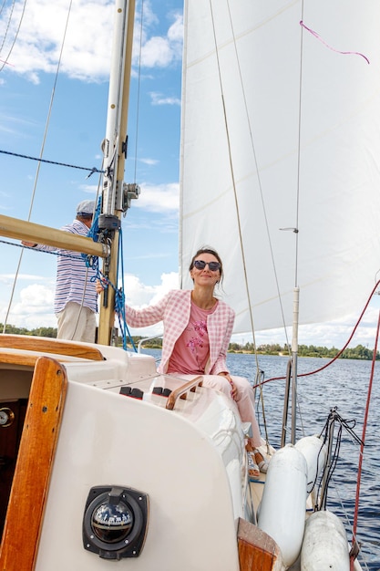 Marin homme dans une casquette avec une fille sur un bateau à voile contre le ciel et l'eau