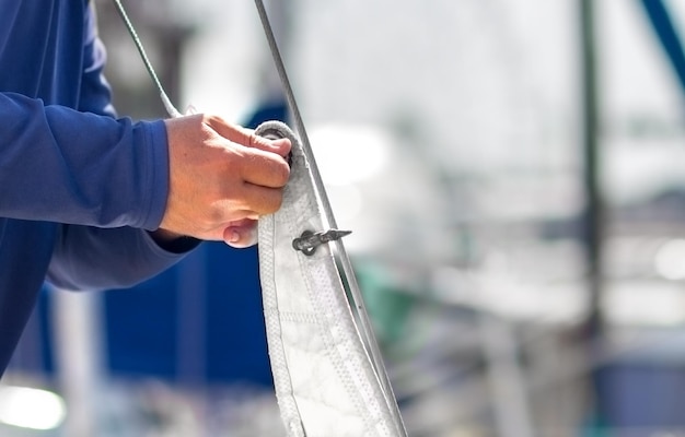 Un marin met les voiles sur un yacht pour une sortie en mer Préparer le navire pour la croisière