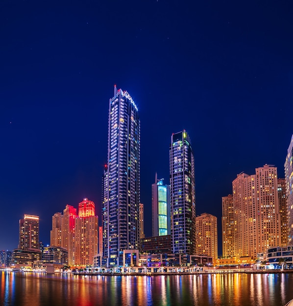 Marina de Dubaï la nuit avec des gratte-ciel, des bateaux et des reflets dans l'eau, Émirats Arabes Unis