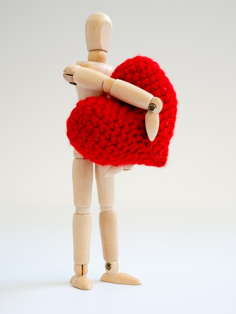 Marionnette en bois debout et tenant un coeur rouge sur le fond d&#39;écran blanc