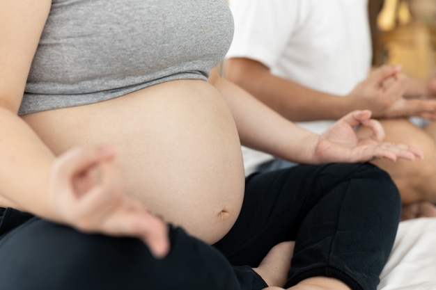 Maris et femmes enceintes de yoga vivant dans la chambre à coucher