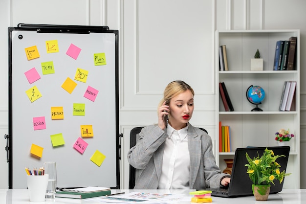 Marketing jolie jeune femme d'affaires en costume gris au bureau en faisant un appel téléphonique