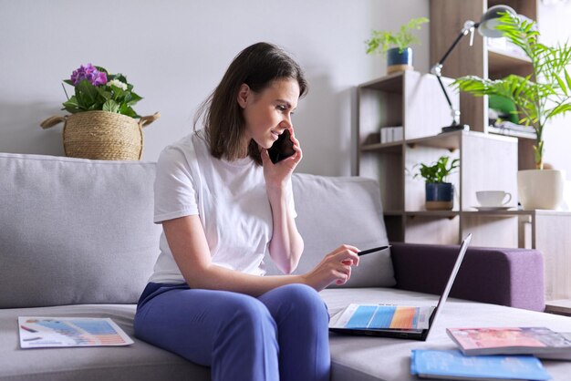 Marketing de réseau domestique en ligne, jeune femme d'affaires indépendante faisant des ventes en ligne à l'aide d'un ordinateur portable et d'un catalogue de produits