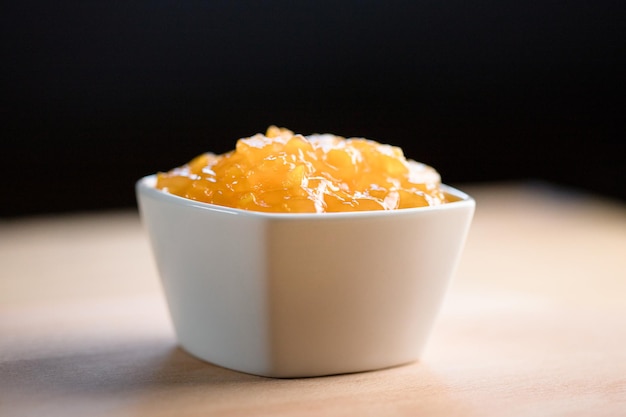 Marmelade de pêches dans un bol sur fond sombre