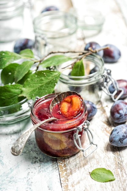 Marmelade de prunes en pot. Confiture de fruits sur fond de bois rustique