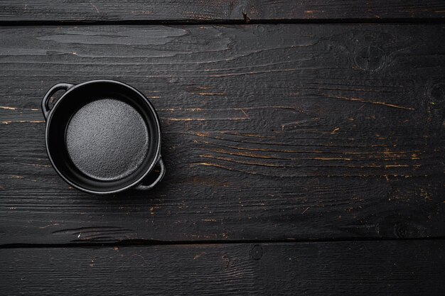 Marmite noire avec espace de copie pour le texte ou la nourriture avec espace de copie pour le texte ou la nourriture, vue de dessus à plat, sur fond de table en bois noir