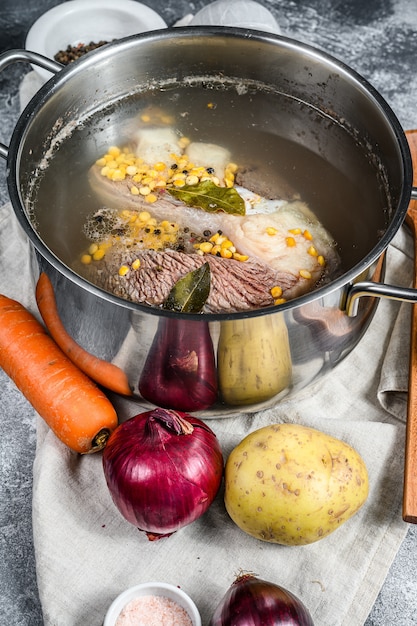 Photo marmite avec de la viande de bouillon d'os. légumes, cuisson des ingrédients et des épices sur la table de la cuisine. vue de dessus