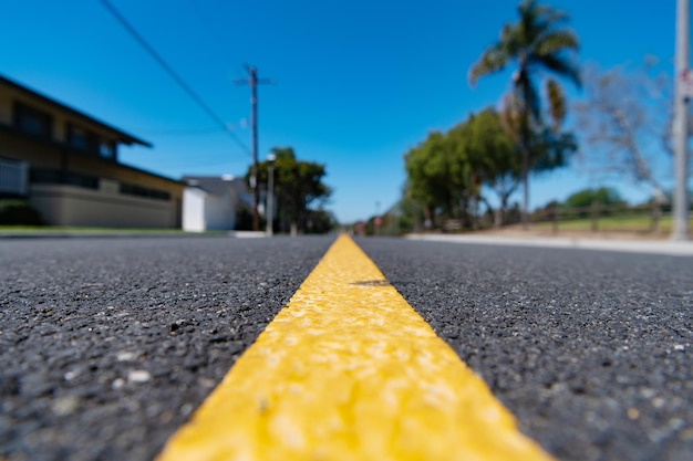 Marquage routier de la ligne jaune sur la route goudronnée le long d'une rue résidentielle floue en banlieue